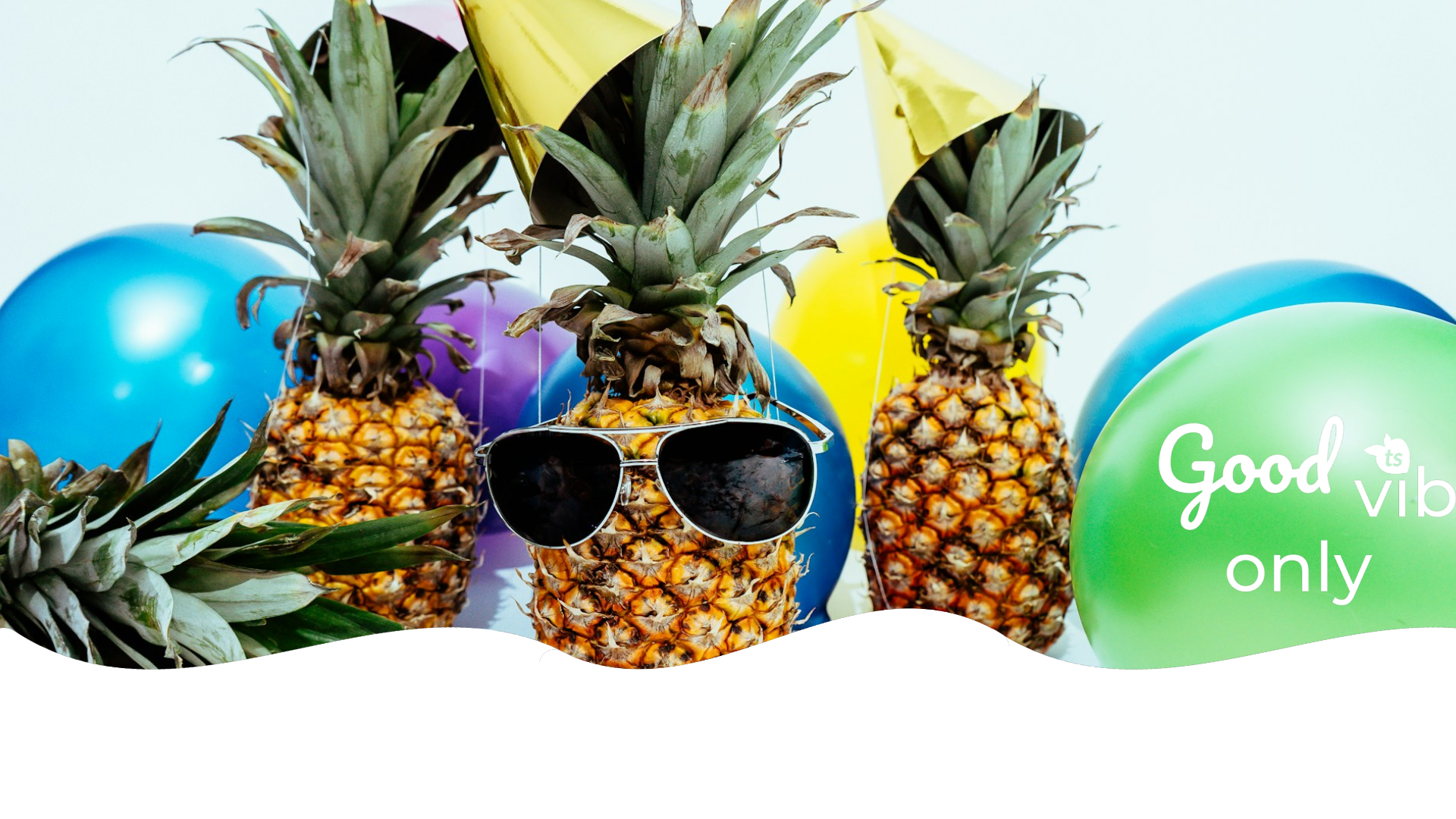 Three pineapples wearing sunglasses with colorful balloons and 'Good Vibes Only' text in the background.